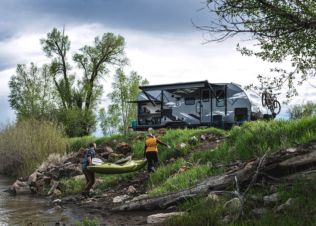 https://www.rvlifemag.com/wp-content/uploads/2022/10/2023-LEAD-PHOTO-Venture-RV-Sonic-X-SN220VRBX-Travel-Trailer-at-Campsite-with-Kayaking-Couple.jpg