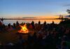 Scouts gather on a beach, around a campfire.