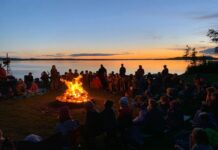 Scouts gather on a beach, around a campfire.