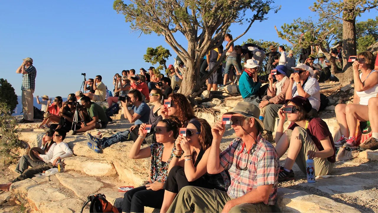 A crowd uses handheld solar viewers and solar eclipse glasses to safely view a solar eclipse. Photo Credit: National Park Service.