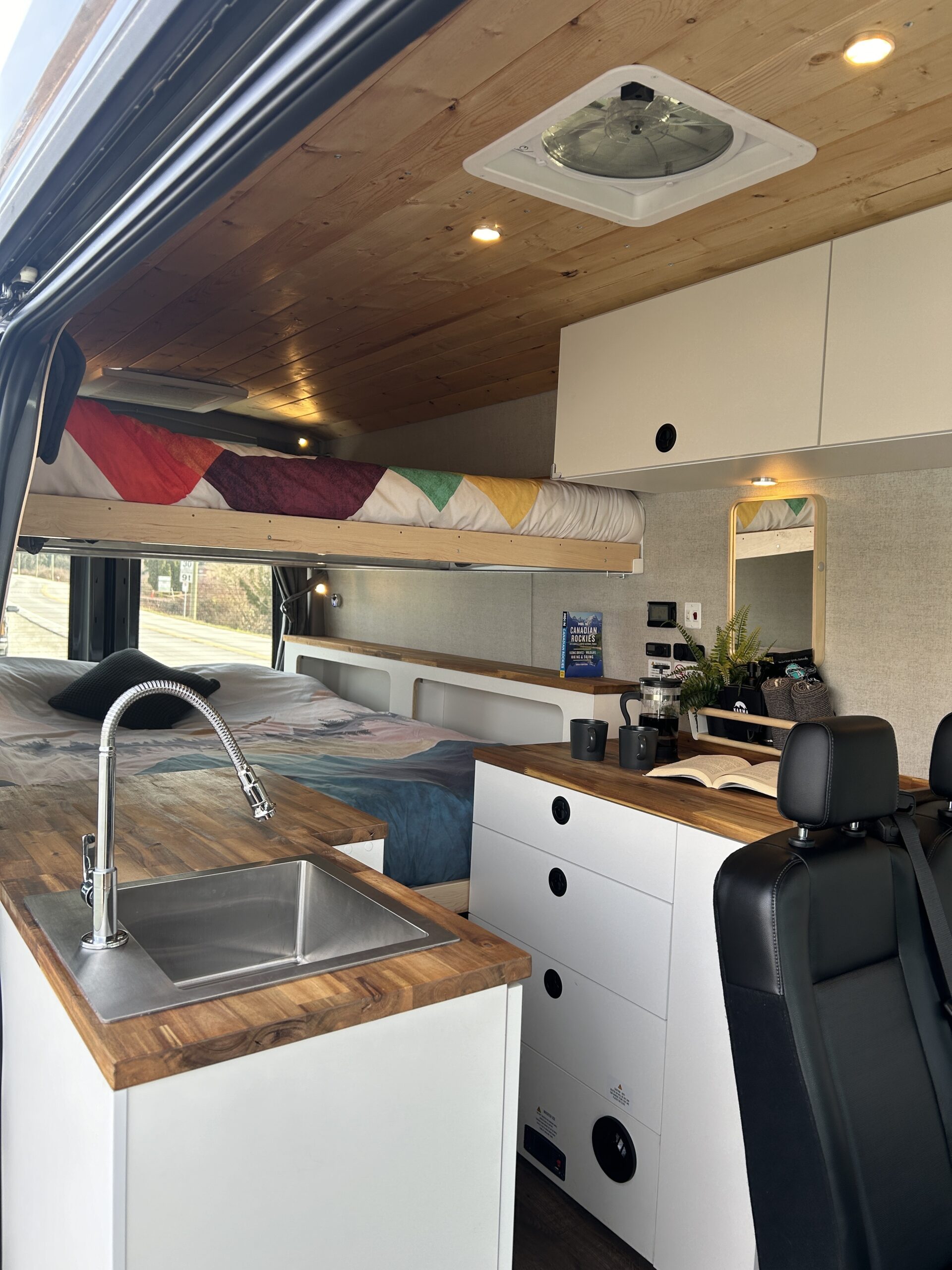 Karma Campervans interior showing galley, queen bunks and seating.