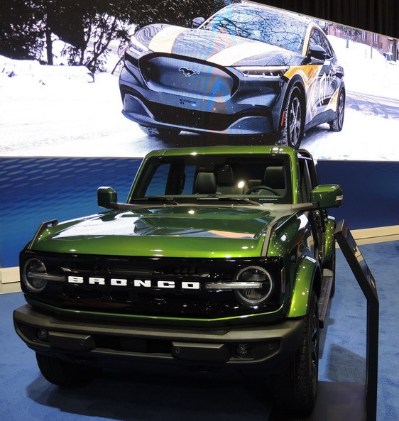 Ford's sporty SUV - the 2026 Bronco, shown here under a projected image of the Mustang EV.